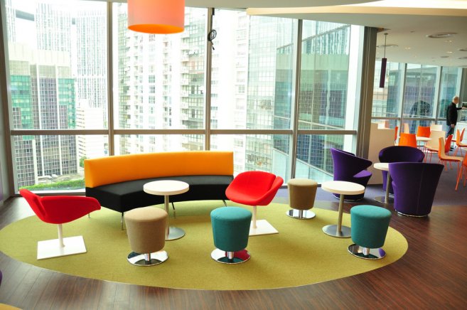 A brightly coloured office common space with chairs and couch