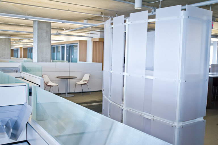 An office space with white cubicles and white modular storage unit