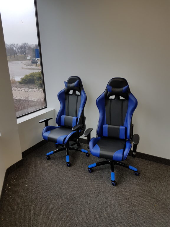 2 black and blue ergonomic desk chairs in an empty office