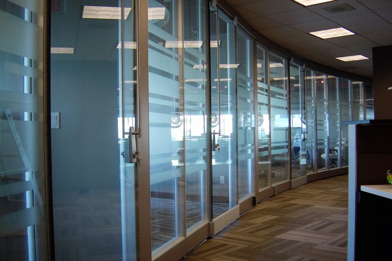 Office hallway with a slightly curved glass wall with some horizontal frosting on the glass.