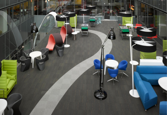 An open office space with brightly coloured chairs and and large lamps