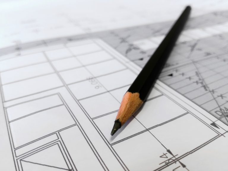 A pencil and a ruler rest on an architectural drawing