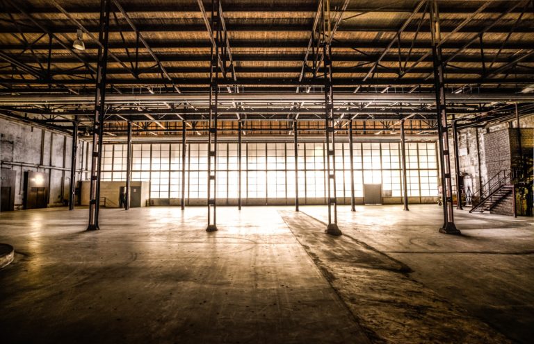An empty warehouse with large windows at the back
