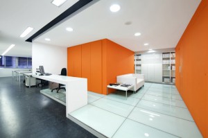 An open office area with white walls and an orange accent wall