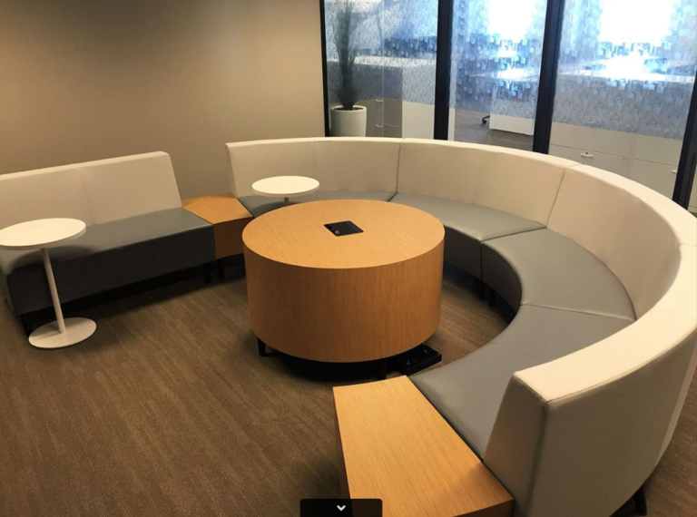 Semi-circular couches surrounding a circular wooden table in an office setting